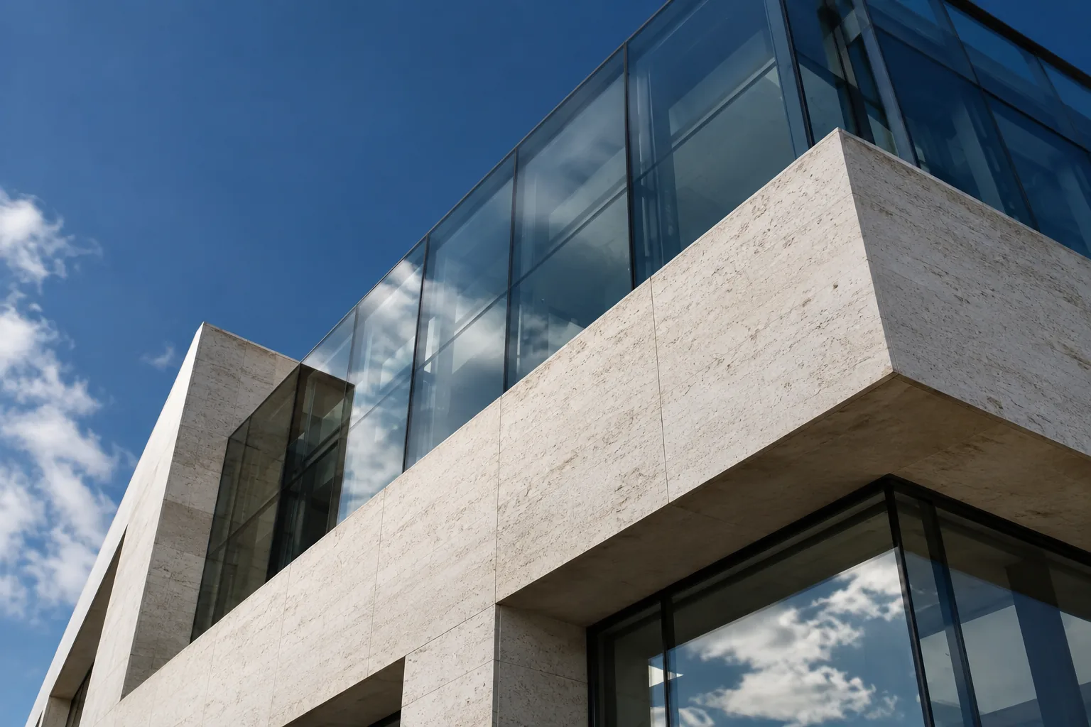 Low-angle view of layered limestone and reflective blue glass